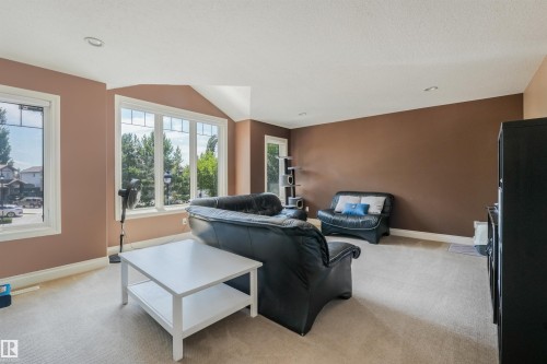 Spacious room featuring broadloom carpeting, a multi-pane bay window, and additional windows with stained-glass accents - 1231 Tredger Crest, Edmonton, AB 