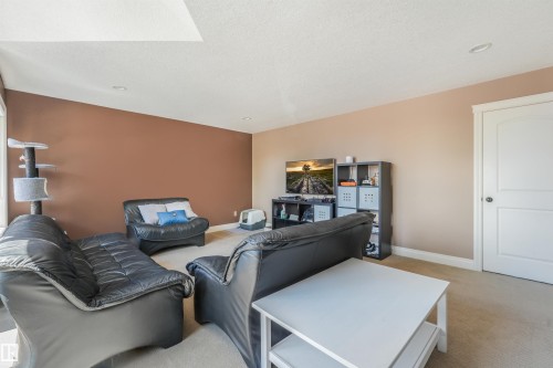 Spacious room featuring neutral carpeting and a sloped ceiling - 1231 Tredger Crest, Edmonton, AB 