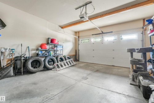 Spacious garage featuring a concrete floor, overhead door with clear window panels, and an automatic garage door opener - 1231 Tredger Crest, Edmonton, AB 