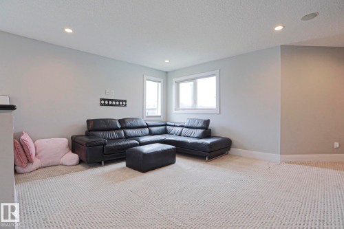 Spacious room featuring light gray walls, white trim, recessed lighting, and two windows providing natural light - 1304 Ainslie Wynd, Edmonton, AB 