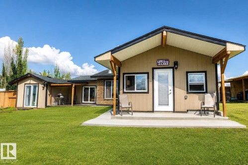 Open-concept living space featuring exposed ceiling beams, hardwood flooring, and abundant natural light from multi-pane windows - 315 57201 Rng Rd 102, Rural St. Paul County, AB 