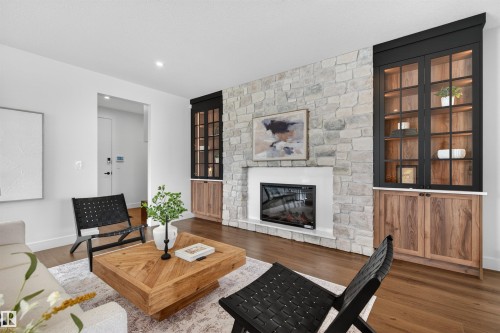 Stone-clad fireplace with a modern linear insert, flanked by custom built-in cabinetry featuring glass-front uppers and wood-finish lower storage - 149 Eastgate Way, St. Albert, AB 