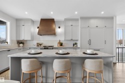 Expansive kitchen island with a stone countertop, surrounded by light-toned cabinetry - 