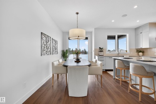 Open-concept dining area with wood-finish flooring, a contemporary drum pendant light, and direct access to an outdoor area - 149 Eastgate Way, St. Albert, AB 