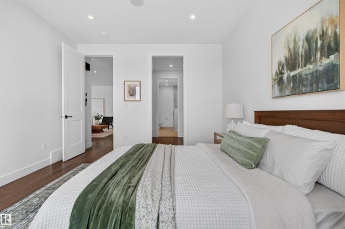 Bedroom featuring wood-finish flooring, recessed lighting, white walls, and a solid wood headboard - 149 Eastgate Way, St. Albert, AB 