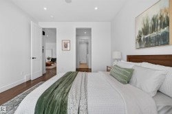 Bedroom featuring wood-finish flooring, recessed lighting, white walls, and a solid wood headboard - 