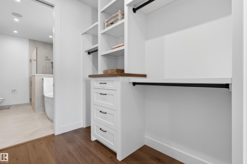 Custom closet system featuring white built-in shelving, integrated drawers with black hardware, and wood-finish countertops - 149 Eastgate Way, St. Albert, AB 