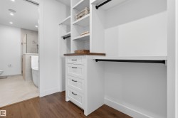 Custom closet system featuring white built-in shelving, integrated drawers with black hardware, and wood-finish countertops - 