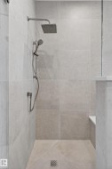 Walk-in shower with large format wall and floor tiling, brushed nickel fixtures, a square rain showerhead, and a handheld shower attachment - 