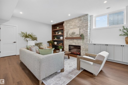 Living area featuring wood-finish flooring, recessed lighting, a stone fireplace with a wood mantle, built-in shelving, and built-in cabinetry - 149 Eastgate Way, St. Albert, AB 