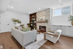 Living area featuring wood-finish flooring, recessed lighting, a stone fireplace with a wood mantle, built-in shelving, and built-in cabinetry - 