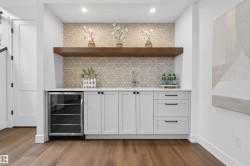 Wet bar featuring light gray cabinetry with black hardware, a built-in beverage cooler, and a single-basin sink - 