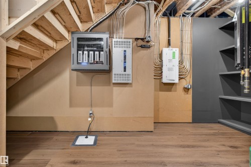 Lower level featuring wood-finish flooring, exposed structural ceiling elements, and a wall-mounted electrical panel - 149 Eastgate Way, St. Albert, AB 
