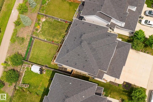 Aerial view showcasing architectural rooflines with dark shingles, landscaped grounds, and paved driveway access - 8589 Cushing Place, Edmonton, AB 