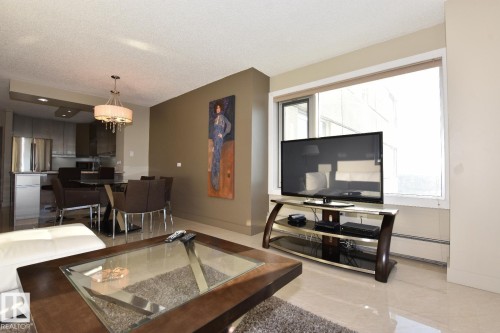 Open-concept living space featuring a dining area with a modern chandelier and a kitchen with stainless steel appliances - 1805 10011 123 Street, Edmonton, AB 