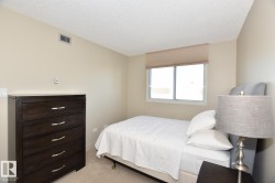 Bedroom featuring neutral toned walls, textured ceiling, a window with a pleated shade, and soft carpet flooring - 