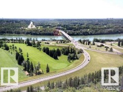 Expansive green space featuring a golf course, mature trees, and a river with a bridge - 