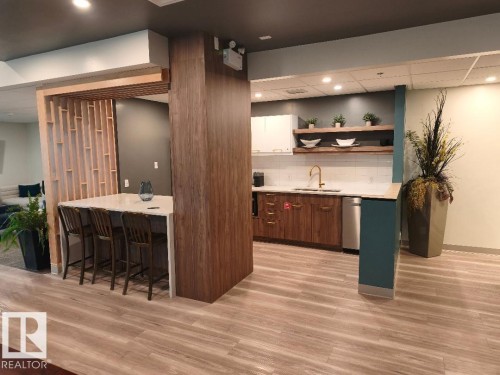 Open-concept common area featuring wood-finish flooring, a kitchen with a white subway tile backsplash, and a breakfast bar with seating - 1805 10011 123 Street, Edmonton, AB 