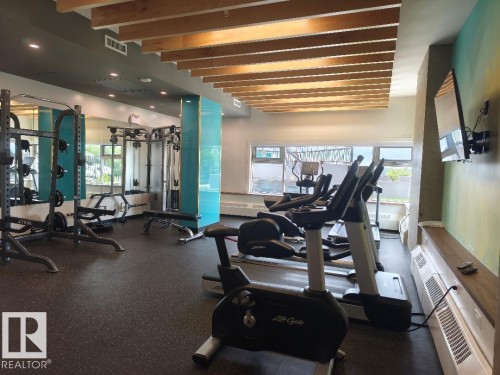 Fitness center featuring rubber flooring, recessed lighting, expansive windows, exposed wood-beam ceiling accents, and mirrored walls - 1805 10011 123 Street, Edmonton, AB 