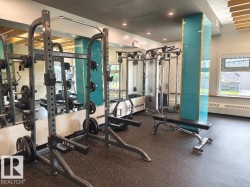 Fitness center featuring weight racks with integrated plate storage, resilient rubber flooring, mirrored walls, and a window for natural light - 