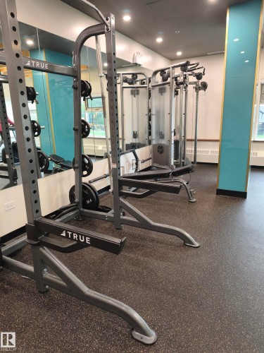 Dedicated fitness space featuring multiple strength training machines, cushioned rubber flooring, and large mirrored walls - 1805 10011 123 Street, Edmonton, AB 