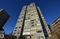 Multi-story residential tower featuring a concrete facade and numerous windows across multiple levels - 