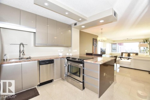 Contemporary open-concept kitchen featuring gloss-finish cabinetry, stainless steel appliances, and a granite countertop island with integrated seating - 1805 10011 123 Street, Edmonton, AB 