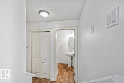 Hallway featuring a bi-fold closet door, textured ceiling, and a flush-mount ceiling light - 2407 Hagen Way, Edmonton, AB 