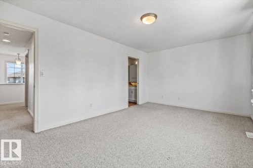 Carpeted room with white walls, baseboards, and a semi-flush mount ceiling light fixture - 2407 Hagen Way, Edmonton, AB 