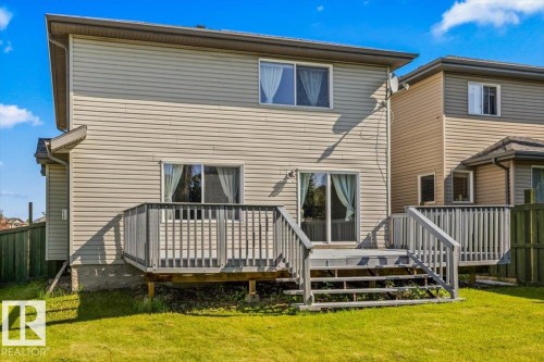 Rear exterior featuring a wooden deck with stairs, a sliding glass door, and a grass lawn - 2407 Hagen Way, Edmonton, AB 