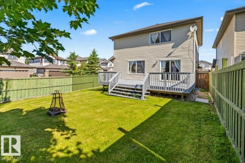 Spacious backyard featuring a green lawn, wood fence, and multi-level deck with stairs - 2407 Hagen Way, Edmonton, AB 