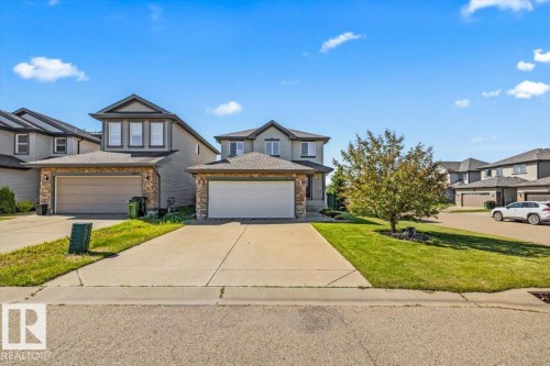 Modern two-story residence with an attached double garage, stone accents on the facade, and a concrete driveway - 2407 Hagen Way, Edmonton, AB 