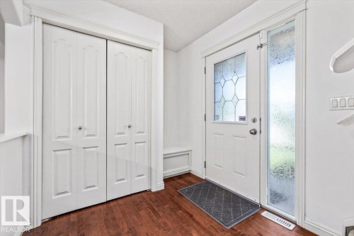 Entryway featuring wood-finish flooring, a white door with decorative glass, and an opaque glass sidelight - 2407 Hagen Way, Edmonton, AB 