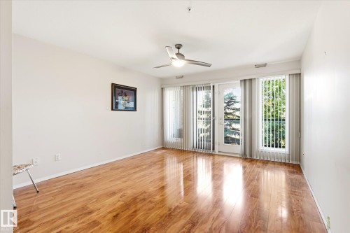 Luminous interior space featuring wood-finish flooring, a ceiling fan with integrated lighting, and white walls - #310 237 Youville Dr E Nw, Edmonton, AB - Indoor Photo Showing Other Room
