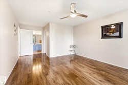 Expansive room featuring wood-finish flooring, a contemporary ceiling fan with integrated lighting, and neutral wall tones - 