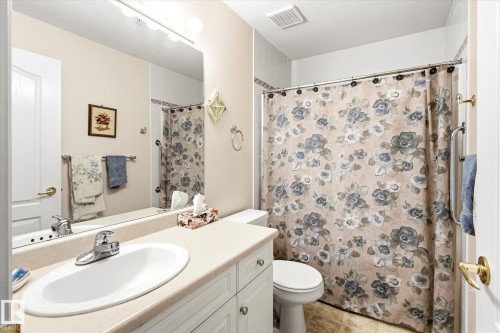 Bathroom with a full vanity featuring an integrated sink, chrome faucet, and cabinet storage - #310 237 Youville Dr E Nw, Edmonton, AB - Indoor Photo Showing Bathroom