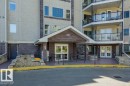 Building exterior featuring a covered entrance with double glass doors, stone column accents, and an overhead address number - 310 237 Youville Drive E, Edmonton, AB 
