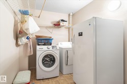 Utility area featuring a washer and dryer, additional freestanding refrigerator, overhead circular lighting, and wall-mounted wire shelving - 