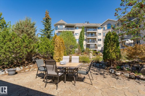 Expansive stamped concrete patio with surrounding garden beds - #310 237 Youville Dr E Nw, Edmonton, AB - Outdoor