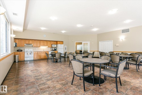 Spacious common area featuring a full kitchen with wood cabinetry, extensive tile flooring, and multiple windows - #310 237 Youville Dr E Nw, Edmonton, AB - Indoor Photo Showing Other Room