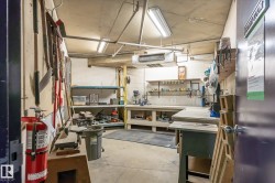 Dedicated workshop space featuring concrete flooring, built-in shelving, two fluorescent light fixtures, and a wall-mounted heater unit - 