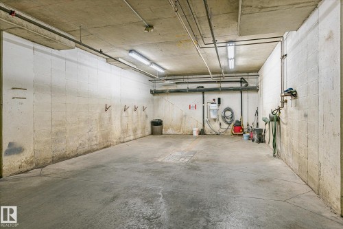 Concrete floor with a visible drainage grate, illuminated by multiple overhead fluorescent light fixtures - #310 237 Youville Dr E Nw, Edmonton, AB - Indoor Photo Showing Garage