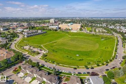 Expansive green space bordered by paved pathways and residential properties - 