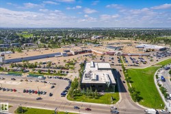 Commercial district featuring multiple retail buildings, expansive paved parking areas, and surrounding green spaces - 