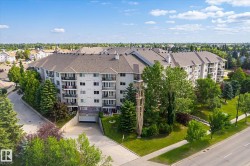 Multi-story residential building featuring balconies, an asphalt shingle roof, and a visible underground parking entrance - 