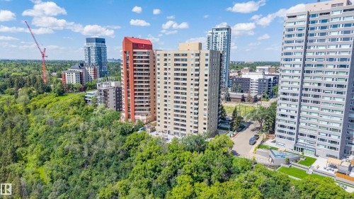 Urban high-rise building with a light-colored facade and numerous balconies, situated on a tree-lined street - 204 12303 Jasper Avenue, Edmonton, AB 