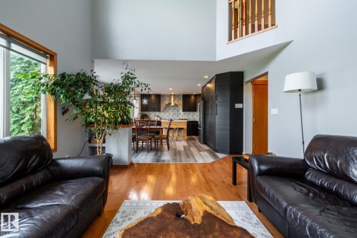 Living area featuring wood-finish flooring, a two-story ceiling, a large window, a partial second-story railing - 114 Reichert Drive, Beaumont, AB 