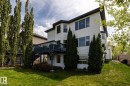 Rear exterior featuring white horizontal siding, a multi-level deck, a walk-out lower level, and mature landscaping - 114 Reichert Drive, Beaumont, AB 