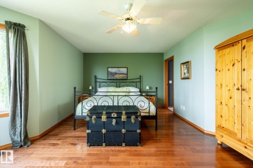 Spacious room featuring wood flooring, a ceiling fan, and a large window with drapes - 114 Reichert Drive, Beaumont, AB 