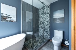 Freestanding soaking tub alongside a walk-in shower with glass enclosure - 